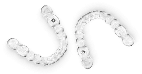 Clear plastic orthodontic aligners displayed in curved formation showing dental treatment progression.